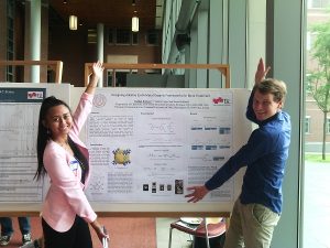 Two students possing in front of their research poster.