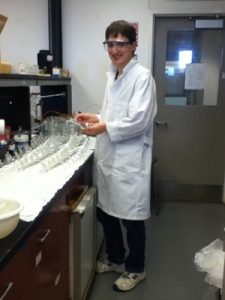 Student in labcoat working with glassware