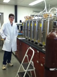 Student in labcoat in front of equipment